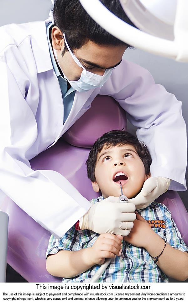 Male dentist examining a Kid patient at clinic