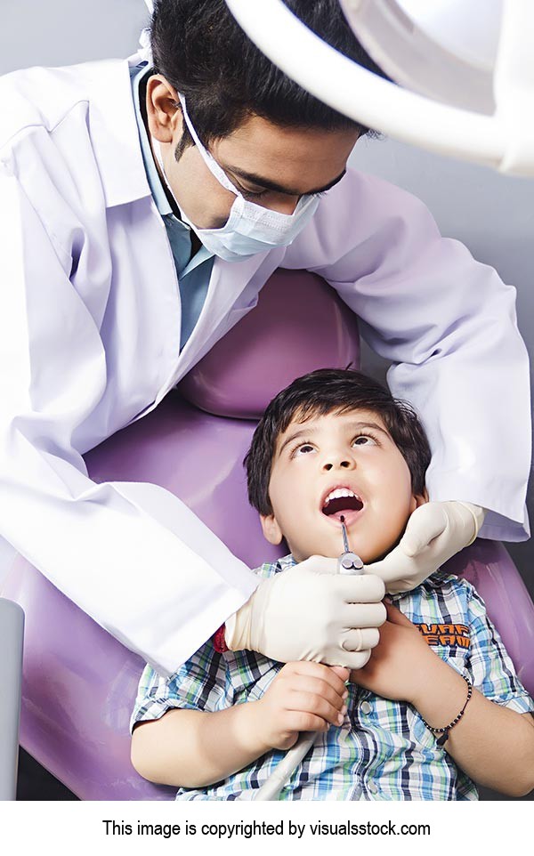 Male dentist examining a Kid patient at clinic