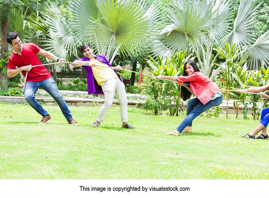 Teenager Friends Playing Tug Of War In Park