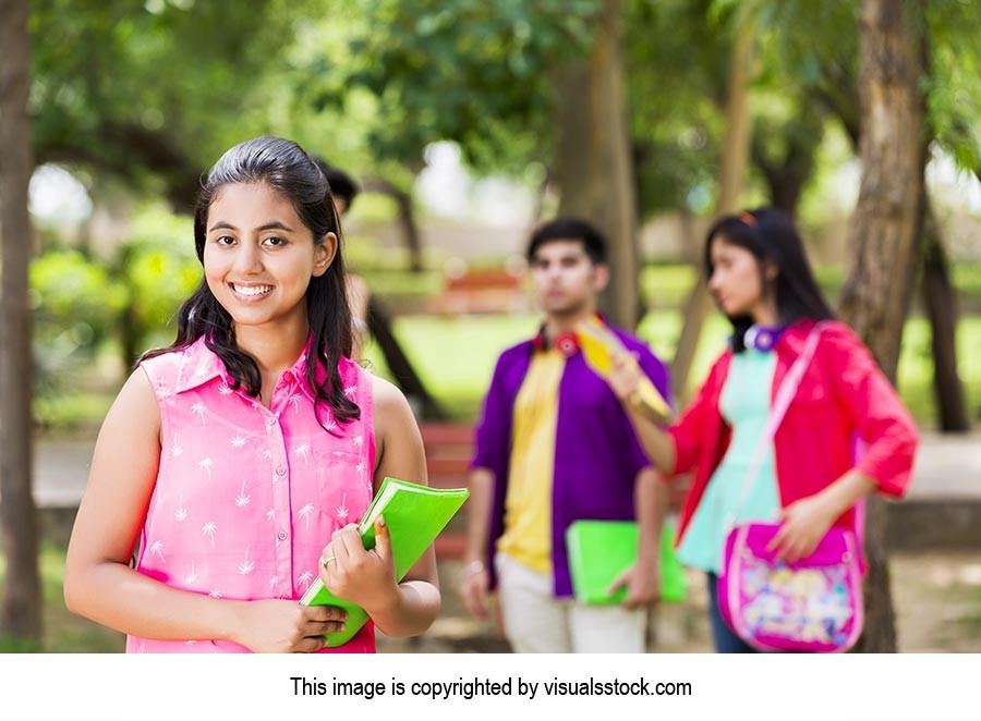 College girl holding books with students in park 