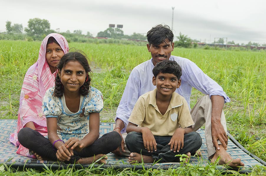 Happy Rural Farmer Family Parents And TwoChildren SittingonCharpai AtFarm