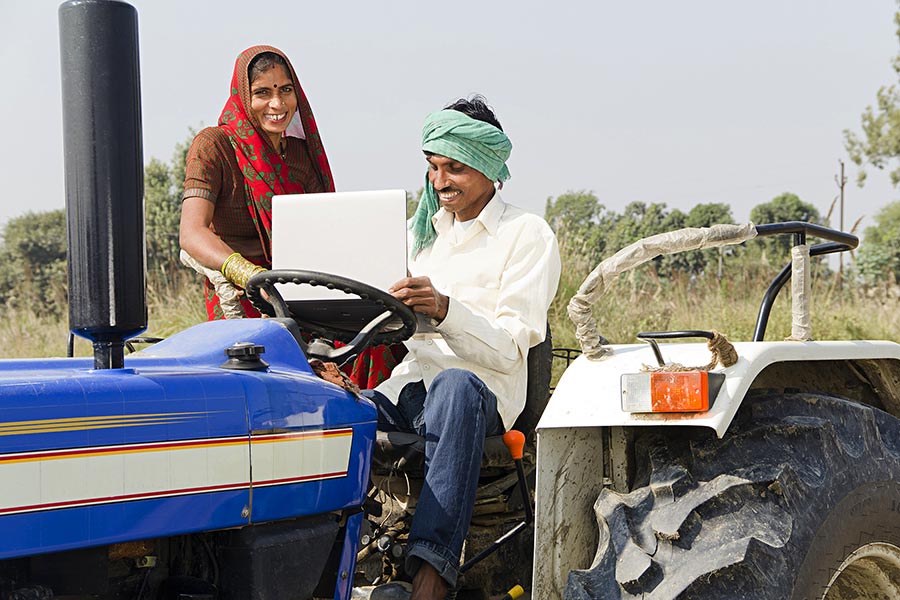 Indain farmer with wife Sitting tractor Using laptop farm Village