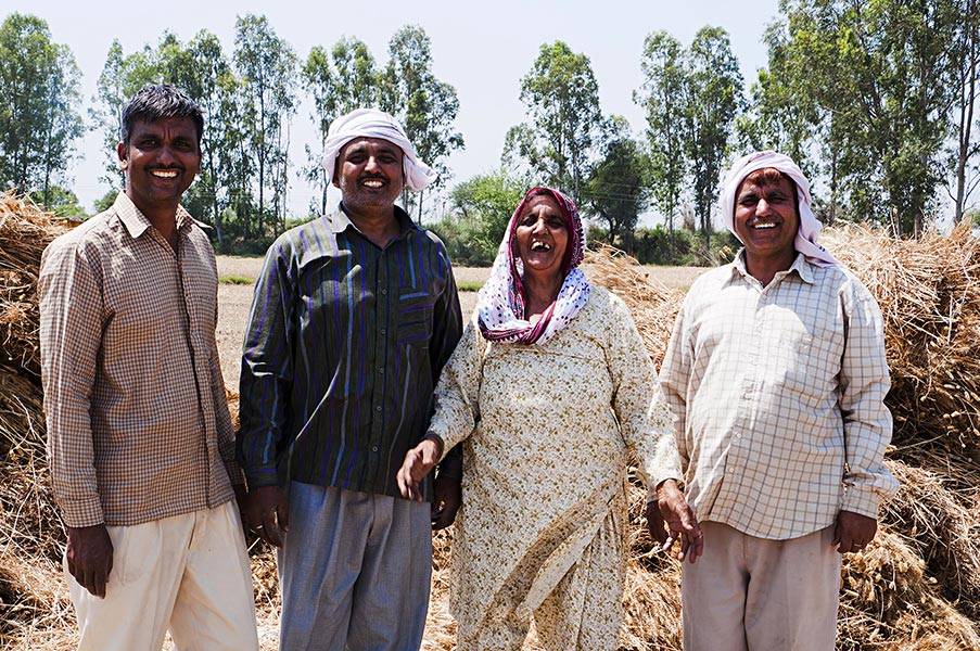 Happy Rural Farmer Family Standing Together inField And Smiling