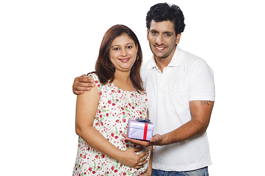 Happy Indian Couple Pregnant Wife And Husband Holding Gift Box