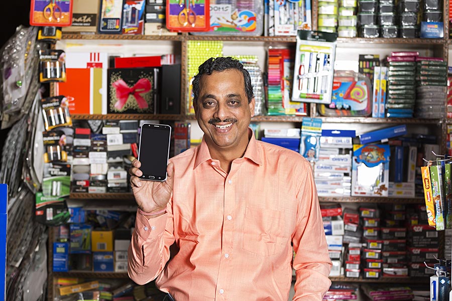 1 Indian Shopkeeper Man Showing Mobile Phone In Stationary Store