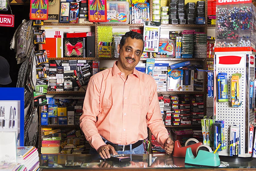 Smiling Indian Shopkeeper Man Using Swap Machine In Stationery Store
