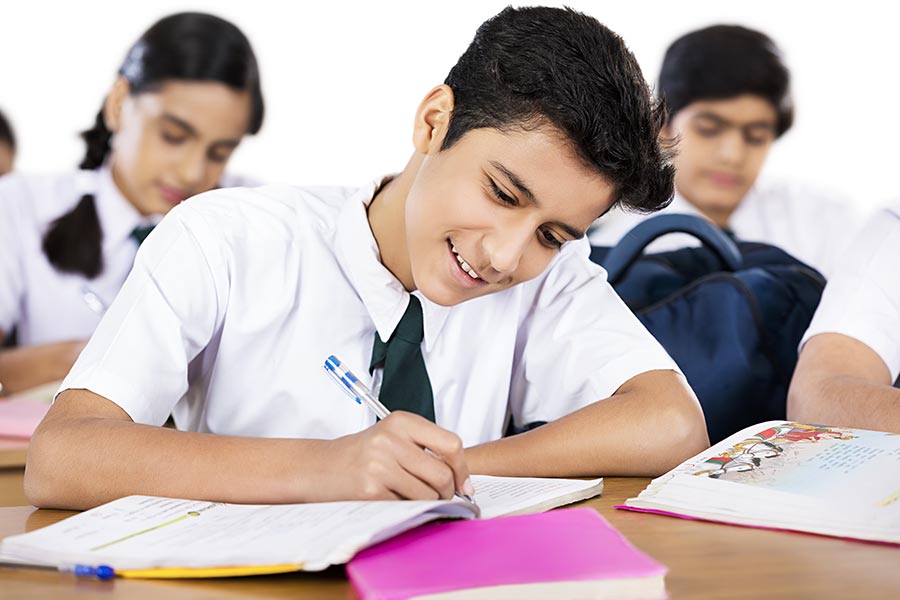 indian-school-boy-student-writing-notebook-studying-with-classmates