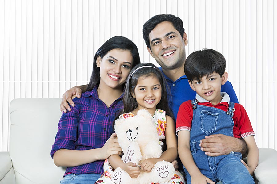 Happy Indian Family Parents And Children Sitting Sofa At Home