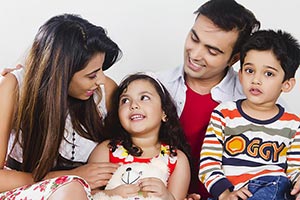 Parents Children Sitting Sofa At Home Smiling