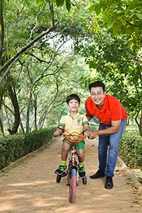 Father Helping Son Riding Bicycle Sidewalk