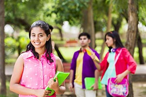 College girl holding books with students in park�